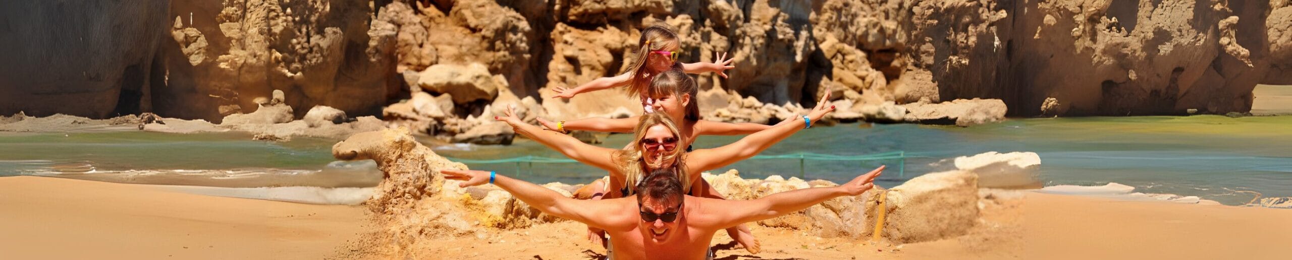 Family stacked on each other's backs with arms spread wide on a rocky beach