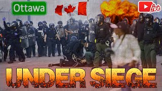 Riot police in full gear confront protesters as flames burn in the background; an Ottawa label, Canadian flags, and large orange 'UNDER SIEGE' text appear in the scene.